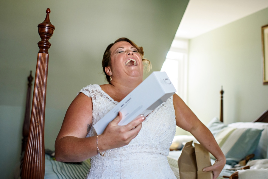 A bride laughing at the gift and note from her fiance.